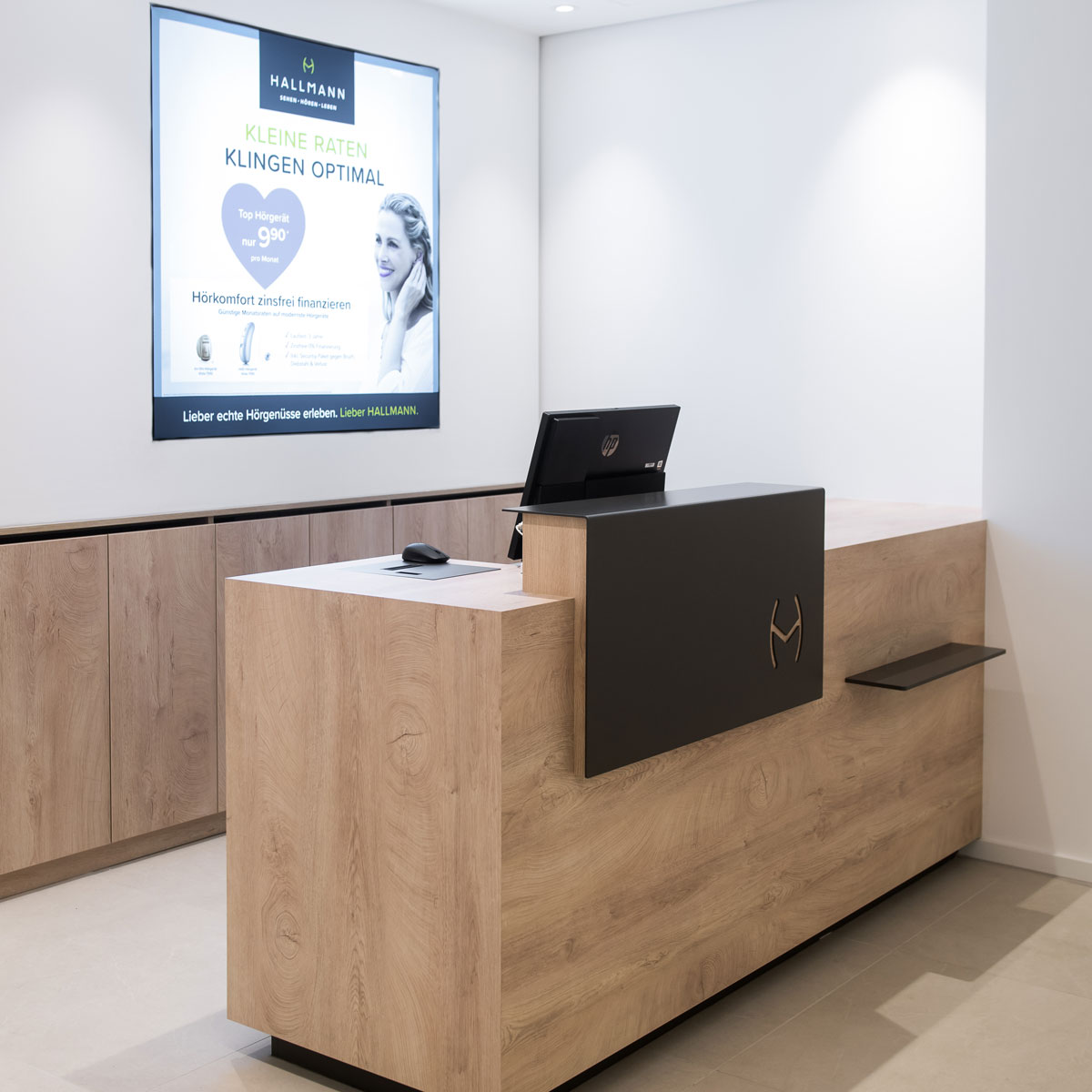 Empfangstheke im modernen Optikergeschäft mit Holzfront und Display